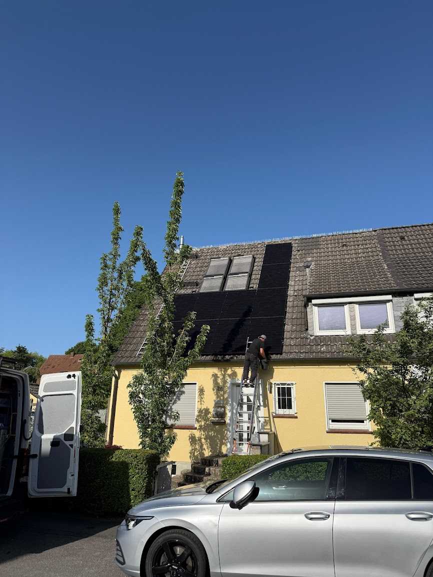 SamBau-Monteur arbeitet auf einer Leiter an der Installation von Photovoltaikmodulen
