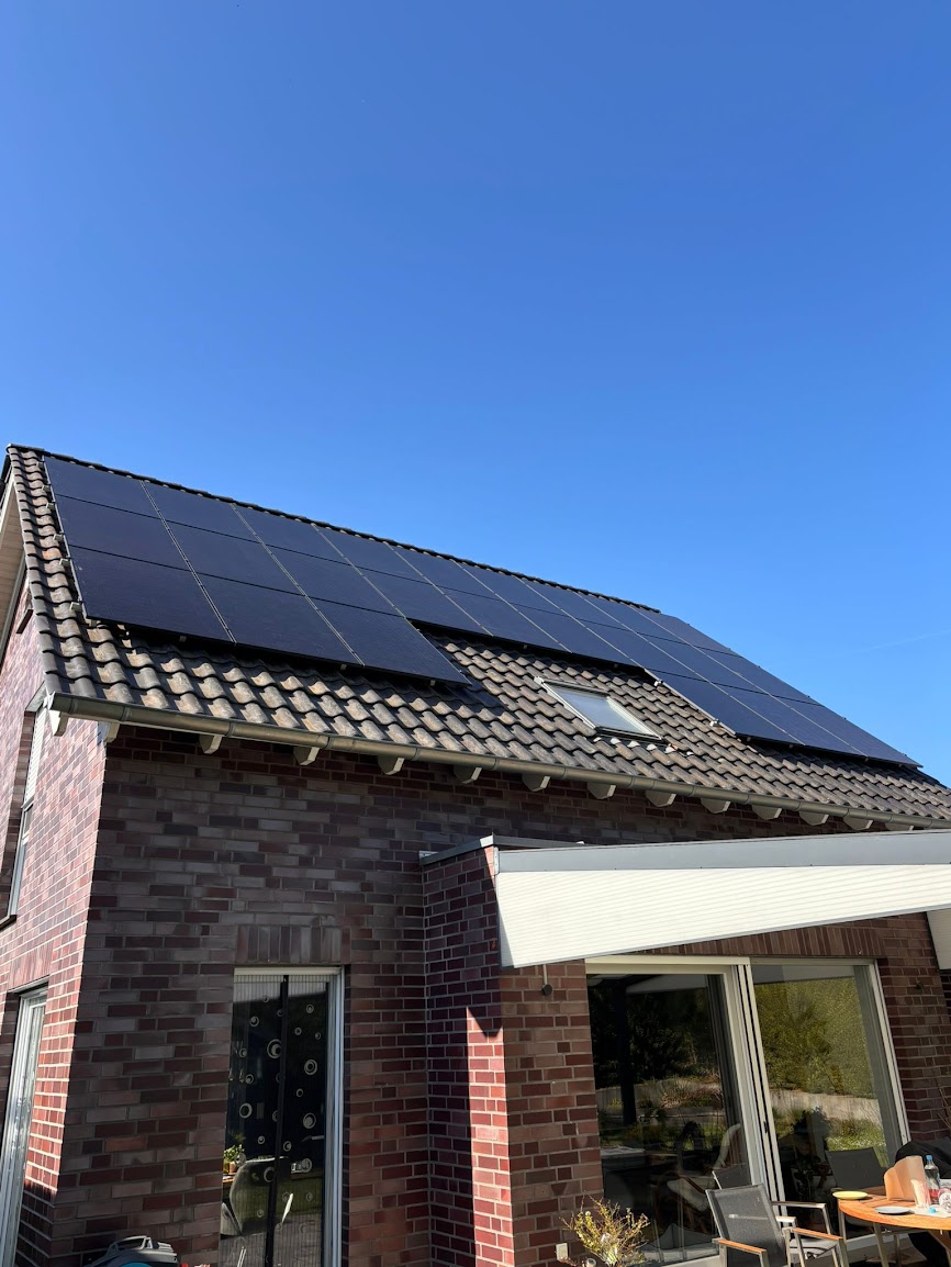Photovoltaikmodule über zwei Dachflächen eines Klinkerhauses mit überdachter Terrasse